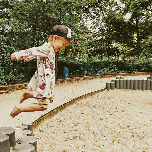 Boy wearing a dress jumping in a playground